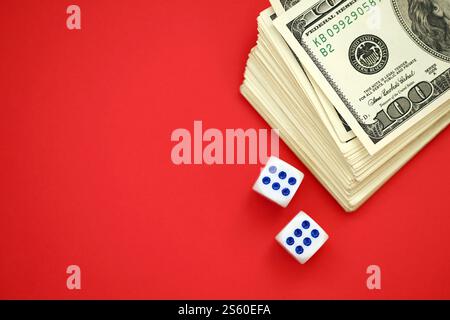 Argent, finance et concept de jeu. Gros plan sur une centaine de billets de banque américains en dollars américains et deux dés blancs sur le dessus montrant les chiffres six et six. Banque D'Images
