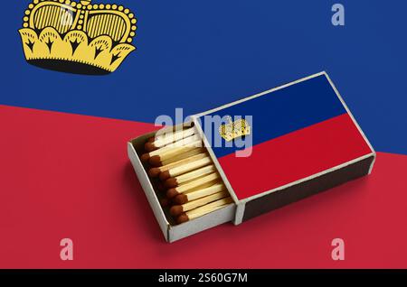 Le drapeau du Liechtenstein est représenté dans une boîte d'allumettes ouverte, remplie d'allumettes et reposant sur un grand drapeau. Le drapeau du Liechtenstein est ouvert Banque D'Images