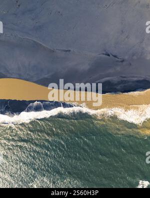 Vue aérienne d'une rivière rencontrant l'océan avec des couleurs contrastées dans le sud de l'Islande. Banque D'Images