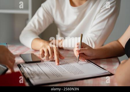 Couple examinant et signant un contrat immobilier ensemble à une table Banque D'Images