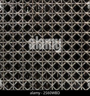 Gros plan d'un motif de grille métallique avec des lignes croisées complexes sur un fond sombre pour le design industriel Banque D'Images