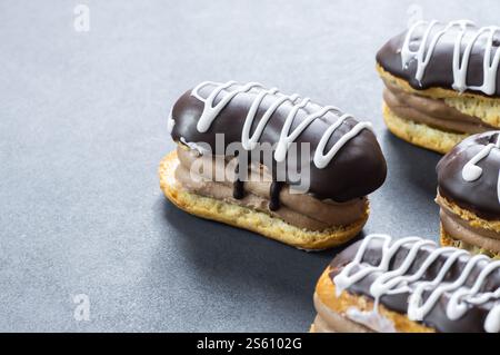 Eclairs au chocolat noir et chocolat blanc avec crème anglaise sur table rustique. Dessert français traditionnel. Concept Eclair Pastery Banque D'Images