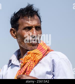Homme en tenue traditionnelle assis à l'extérieur contre un mur altéré dans un cadre de village indien Banque D'Images