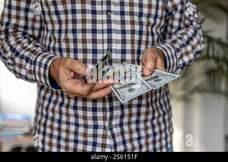 Permettez-moi de vérifier cet argent : gros plan d'un homme vérifiant une liasse de billets de 100 dollars américains. Cash in Hand concept - salaires, paiement, dividendes ou prêt. Banque D'Images
