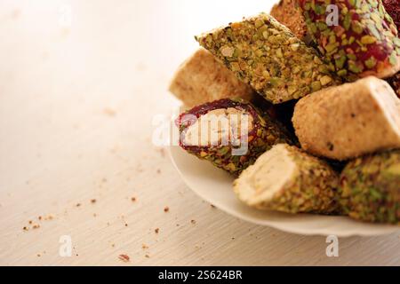 De nombreux rouleaux de plaisir turc avec différentes saveurs et garnitures dans une assiette blanche sur la table. Coupes de bonbons Turk Lokumu. Beaucoup de petits pains de plaisir turc Banque D'Images
