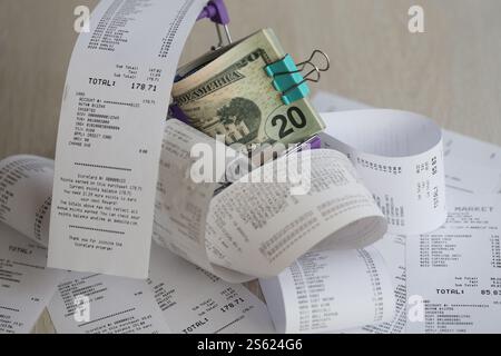 Paquet de dollars AMÉRICAINS dans le chariot de shopping entouré de nombreux reçus papier de près. Paquet de dollars US dans le chariot de shopping entouré de beaucoup de papier Banque D'Images