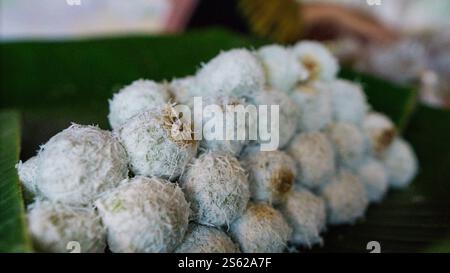 Un tas de bonbons klepon traditionnels indonésiens, recouverts de noix de coco râpée, sur des feuilles de bananier. Banque D'Images