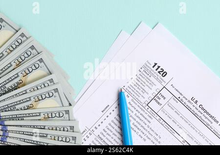 1120 formulaire d'impôt se trouve près de cent billets de dollars et stylo bleu sur un fond bleu clair. Déclaration de revenus des sociétés AMÉRICAINES. 1120 formulaire d'impôt se trouve près Banque D'Images
