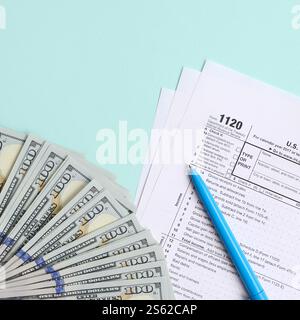 1120 formulaire d'impôt se trouve près de cent billets de dollars et stylo bleu sur un fond bleu clair. Déclaration de revenus des sociétés AMÉRICAINES. 1120 formulaire d'impôt se trouve près Banque D'Images