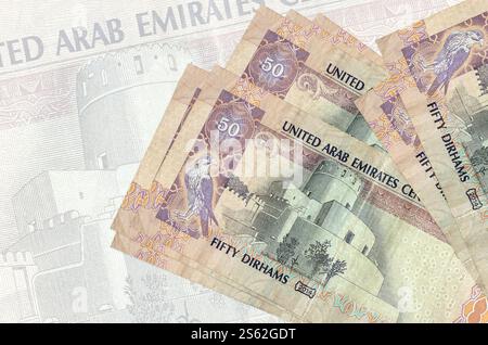 50 billets de dirhams des Émirats arabes Unis se trouvent en pile sur fond de gros billet de banque semi-transparent. Présentation abstraite de la monnaie nationale. Concept commercial. 50 Banque D'Images