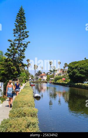 Immobilier résidentiel haut de gamme côté canal le long des jolis canaux à Venise, Los Angeles, Californie, côte ouest des États-Unis. Trois personnes marchant le long du chemin de halage. Banque D'Images