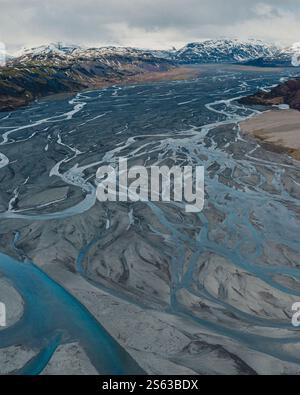 Vue aérienne des rivières tressées qui traversent Jokulsasandur, Lon, est de l'Islande, avec des montagnes enneigées et un ciel spectaculaire. Banque D'Images