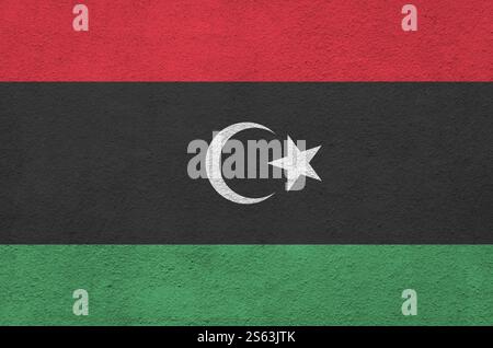 Drapeau libyen représenté dans des couleurs de peinture vives sur le vieux mur de plâtrage en relief en gros plan. Bannière texturée sur fond brut. Drapeau libyen représenté en Bright Banque D'Images