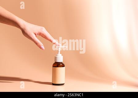 Distributeur de lotion pour corps de pompe à main femelle avec étiquette vierge, fond rose beige avec des ombres, espace de copie. Femme appliquant le produit de soins du corps, beautés quotidiennes Banque D'Images