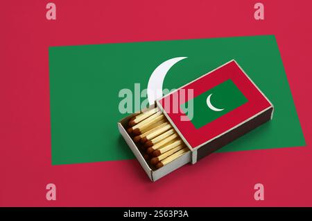 Le drapeau des Maldives est montré dans une boîte d'allumettes ouverte, qui est remplie d'allumettes et repose sur un grand drapeau. Le drapeau des Maldives est montré dans une boîte d'allumettes ouverte, qui Banque D'Images