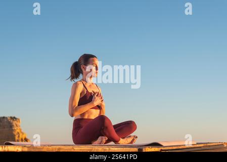 belle femme adulte moyenne assise méditant au lever du soleil Banque D'Images