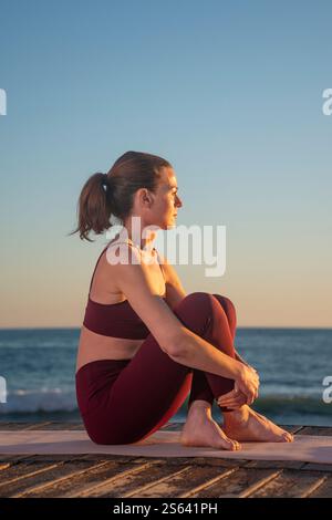 femme sportive assise sur son tapis d'exercice se reposant en regardant le coucher du soleil lever Banque D'Images