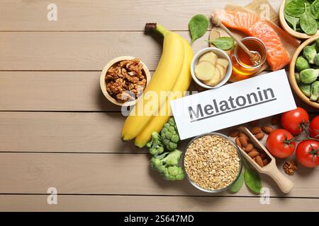 Mot mélatonine et différents produits sur table en bois, pose à plat Banque D'Images
