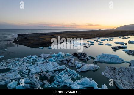 Vue aérienne à couper le souffle de la lagune du glacier Jokulsarlon au coucher du soleil, icebergs flottant dans les eaux sereines de la destination touristique la plus populaire d'Islande. Banque D'Images