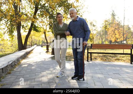 Soignant aidant l'homme âgé dans le parc. Service de soins à domicile Banque D'Images