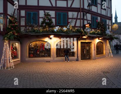 Colmar, France - 26 décembre 2024 : homme regardant une vitrine de magasin de Noël décorée d'ornements et de lumières festifs à Colmar Banque D'Images