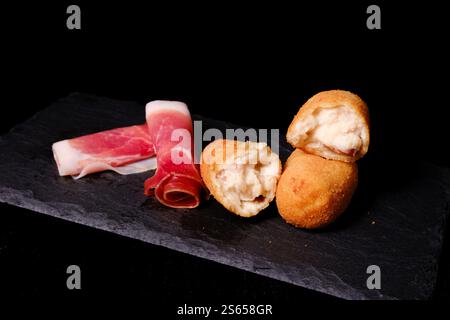 Croquettes de jambon avec des tranches de jambon séché sur une assiette en ardoise Banque D'Images