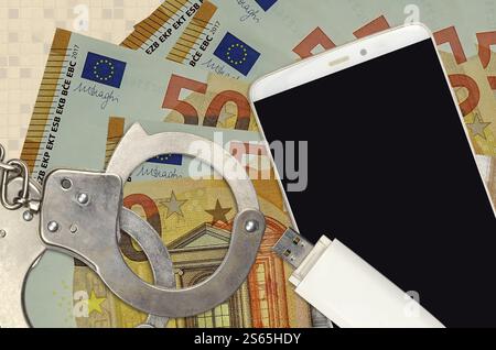 billets de 50 euros et smartphone avec menottes policières. Concept de pirates informatiques attaques de phishing, arnaque illégale ou distribution logicielle de logiciels espions en ligne. 50 euros Banque D'Images