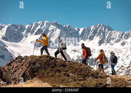 Groupe de jeunes amis randonneurs avec sacs à dos marche en montée contre le glacier de montagne et le ciel bleu Banque D'Images