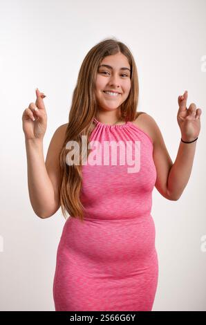 Photo studio d'une jeune femme joyeuse croisant les doigts et faisant un vœu Banque D'Images