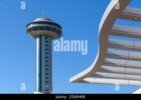 Abu Dhabi, eau - 3 janvier 2025 : une tour d'observation moderne se dresse contre un ciel bleu clair, avec une structure architecturale élégante dans le foregro Banque D'Images