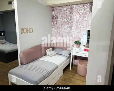 Une chambre magnifiquement conçue avec un style boho avec un décor rose, un lit confortable et des accents floraux, créant une atmosphère confortable et élégante. Banque D'Images