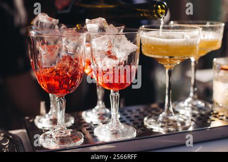 Barman travaillant, belle ligne de rangée de cocktails d'alcool de différentes couleurs sur une fête en plein air dans un bar, et d'autres sur le banquet de restauration sur e. Banque D'Images