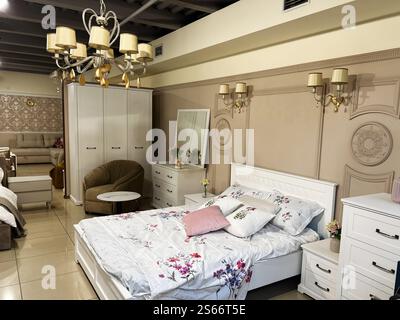 Charmant intérieur de chambre avec un lit blanc, un décor élégant et des luminaires dorés, créant une atmosphère confortable et sophistiquée. Parfait fo Banque D'Images