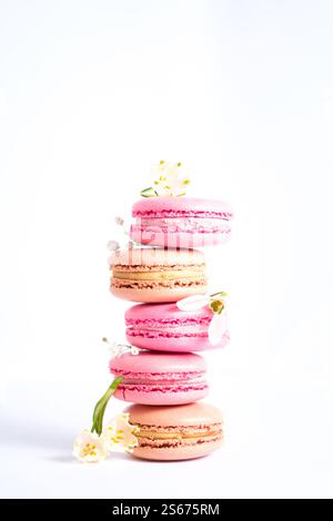 Macarons roses et beiges et fleurs de printemps sur fond blanc, esthétique photographique. Banque D'Images