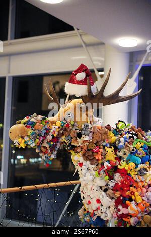 Sculpture d'orignal créative recouverte de jouets en peluche avec chapeau de Père Noël dans un cadre festif Banque D'Images