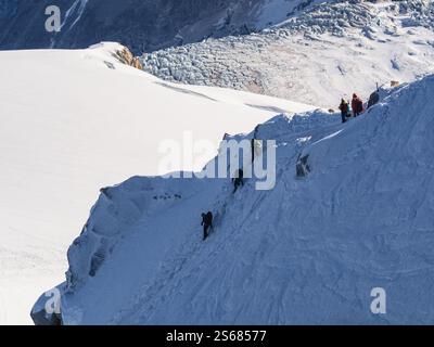 Grimpeurs gravissent les pentes escarpées et enneigées de l’aiguille du midi – Un défi alpin pur au cœur de Chamonix Banque D'Images
