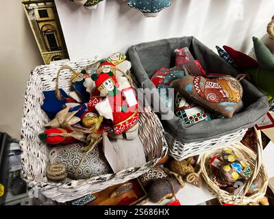 Des ornements festifs sont affichés dans des paniers en osier, présentant des motifs colorés fabriqués à la main dans diverses formes. Idéal pour les décorations de vacances et Evokin Banque D'Images