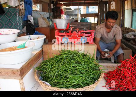 Un homme indonésien vendant des piments verts et rouges frais dans un marché traditionnel à Bukittinggi, Sumatra Ouest, Indonésie. Banque D'Images