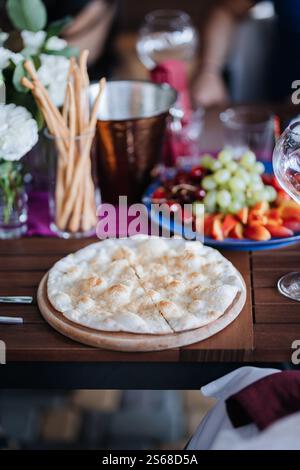 Délicieux pain plat servi avec des fruits frais et des gressins sur une table à manger magnifiquement dressée Banque D'Images
