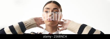 Une jeune femme exprime des émotions audacieuses, les mains près de son visage, rayonnant de confiance. Banque D'Images