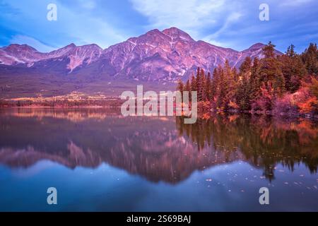 La lumière de l'aube baigne Pyramid Lake dans le parc national Jasper, Alberta, Canada, reflétant le feuillage automnal vibrant et les sommets majestueux dans son calme et vitreux Banque D'Images