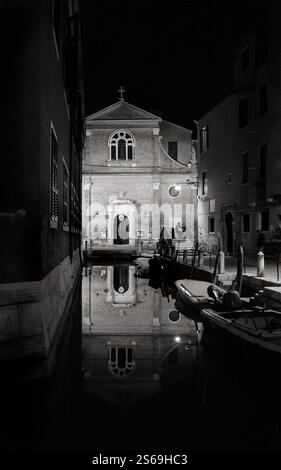 Réflexions du paysage de Venise. Église San Martino reflétée dans l'eau du canal la nuit en hiver. Venise, Italie. Photo historique noir et blanc. Banque D'Images
