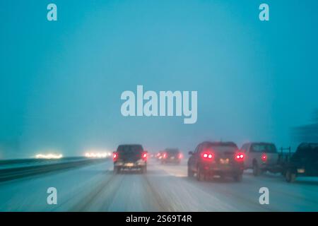 Conduite dans de mauvaises conditions météorologiques avec de la neige sur autoroute de nuit, flou de mouvement à longue exposition dans l'appareil photo Banque D'Images