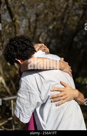 Deux hommes se serrant dans un parc, montrant amour et affection Banque D'Images