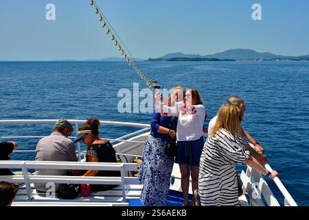 Sarande, Albanie - 6 juin 2024. Les voyageurs d'une journée prennent un ferry le matin pour la vieille ville de Corfou pour une journée. Ville de Corfou et l'île de Vido à l'horizon Banque D'Images