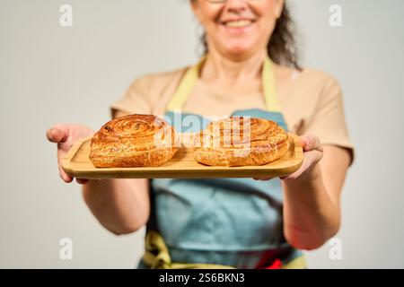 Femme tenant un plateau en bois avec deux rouleaux de cannelle dessus Banque D'Images