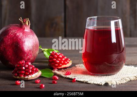 Verre de jus de grenade et fruits de grenade mûrs frais sur fond de bois foncé, concept de boisson saine, (granatum Punica) Banque D'Images