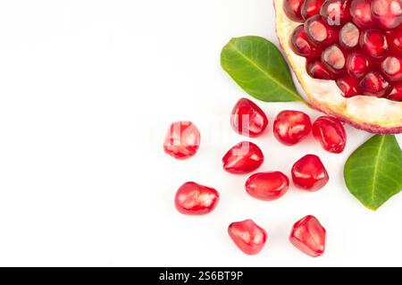 Grenade juteuse fraîche mûre entière et fendue avec des graines et des feuilles isolées sur fond blanc, concept de fruits rouges sains (Punica granatum) Banque D'Images