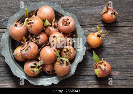 Fruit de nèfle commun biologique frais mûr dans une assiette ou un bol sur fond rustique en bois. Nourriture saine Mespilus germanica Banque D'Images