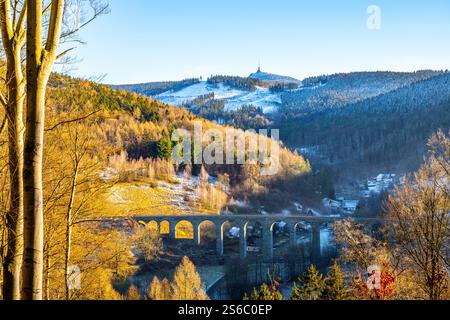 Un magnifique coucher de soleil d'hiver illumine le pont de pierre ferroviaire de Novina, sur fond de montagne Jested. Le paysage présente des arbres givrés et des vallées tranquilles. Banque D'Images